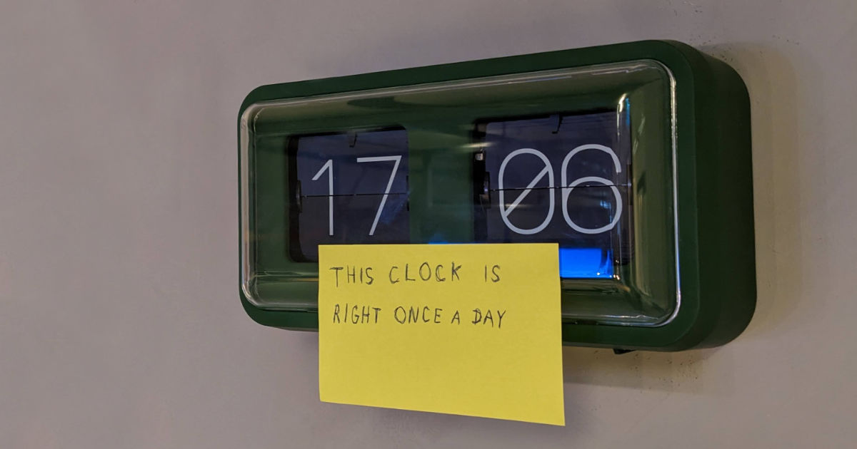 A photo of a broken clock with a sticky note on it say: this clock is right once a day.